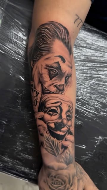 Joker and comedy mask forearm tattoo in black and grey
