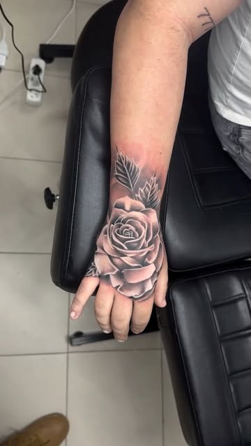 Black and grey rose tattoo on a hand