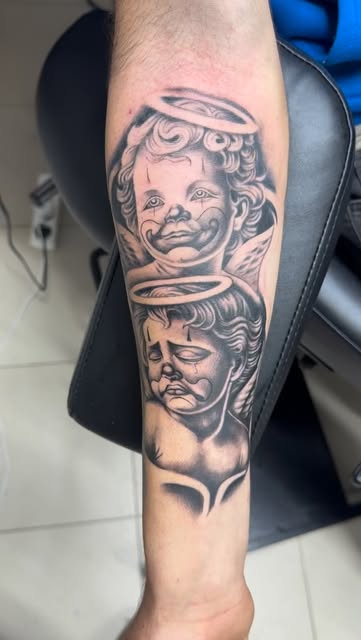 Twin cherubs with halos, black and grey forearm tattoo